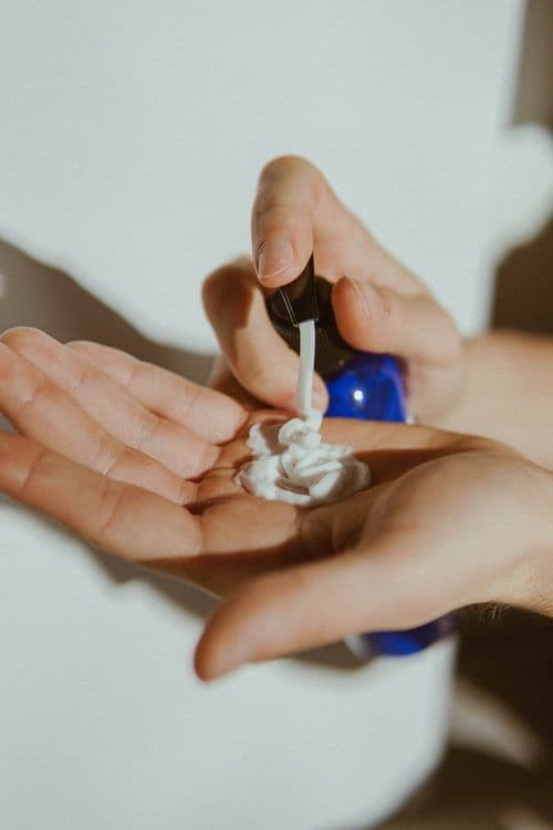 A closeup of cream being squeezed from the container into a hand