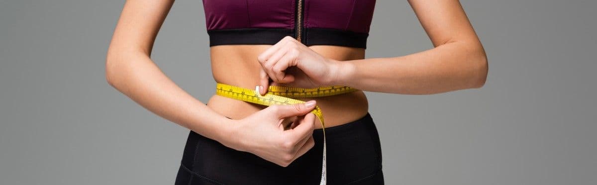 A women holding a tape measure around midrift